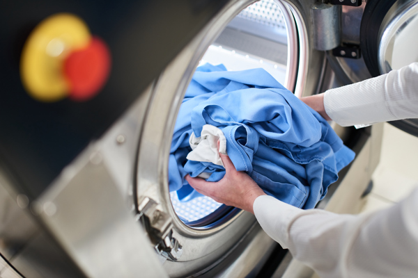 Hands Loading Laundry Into Washing Machine Dry Cleaning
