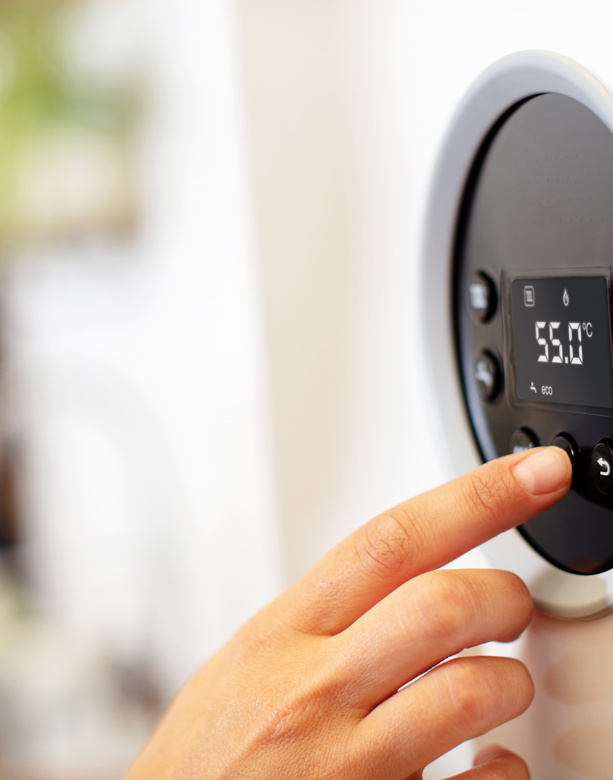 Solar PV Engineer, kneeling next to solar panels, wearing workwear and an orange high viz jacket and white hard hat.