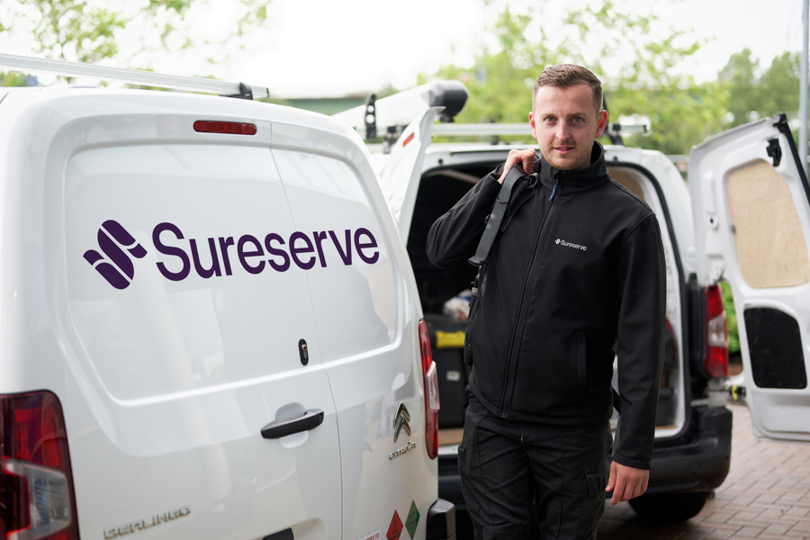 Engineer by Sureserve van carrying tool bag in black jacket and trousers