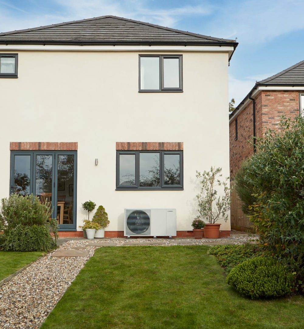 White house with black framed windows and heat pump on ground